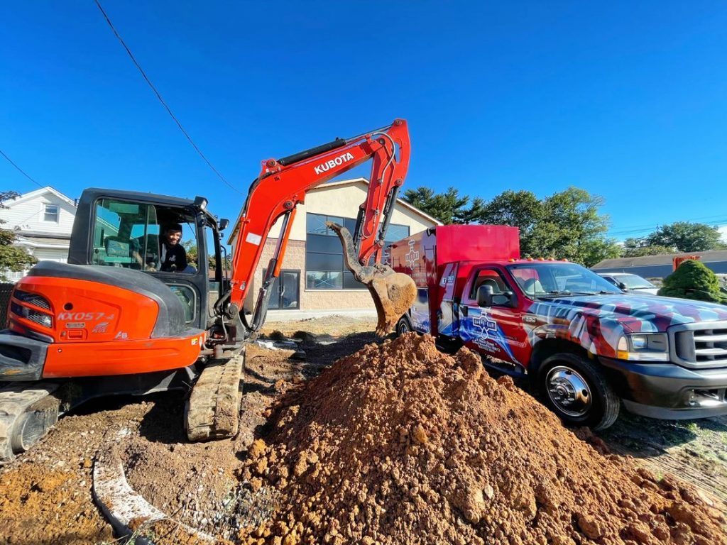 An Arrow Sewer & Drain excavator adding dirt to a pile