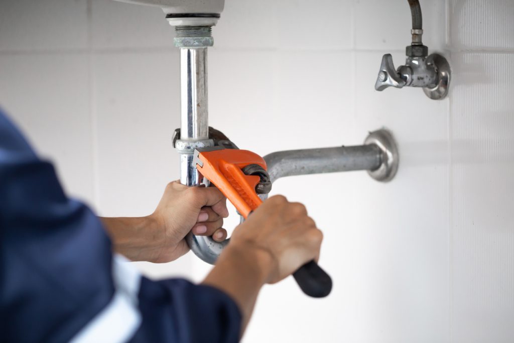 Plumber tightening pipe with wrench