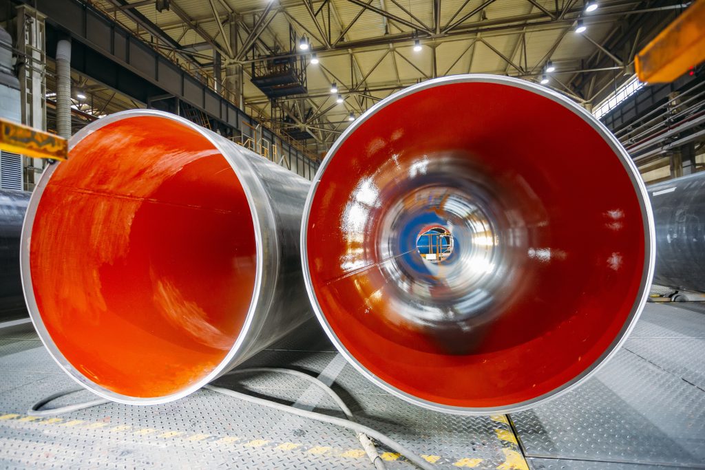 Two large diameter pipes sit in well-lit warehouse