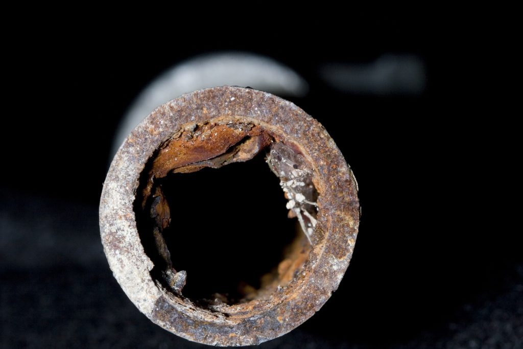 Heavily corroded pipe against black background