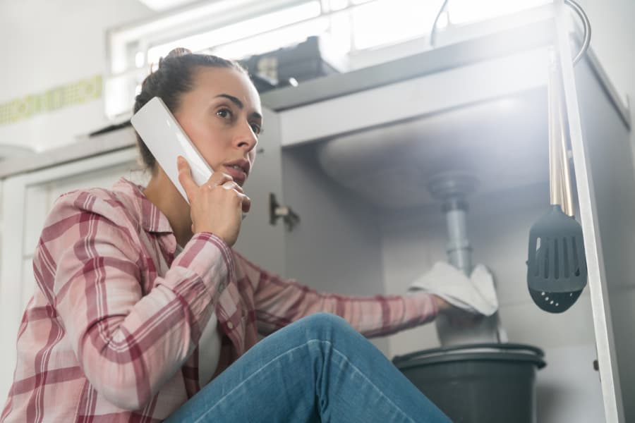 Homeowner on the phone with plumber after experiencing slow-moving drainage