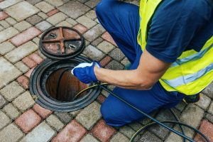 Plumbing professional inserting sewer scope and camera into manhole