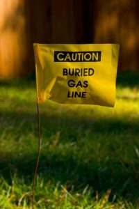Yellow caution flag posted stacked in grass indicating nearby utility line