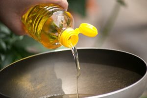 Person pouring cooking oil into pan