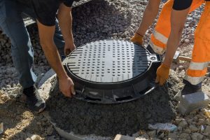 Workers putting lid on septic tank