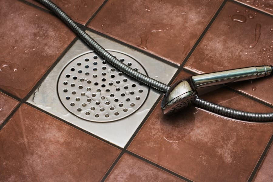 Shower drain with handheld showerhead laying nearby