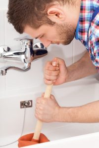 homeowner-attempting-to-unclog-bathtub-drain-with-plunger Homeowner attempting to unclog bathtub drain with plunger